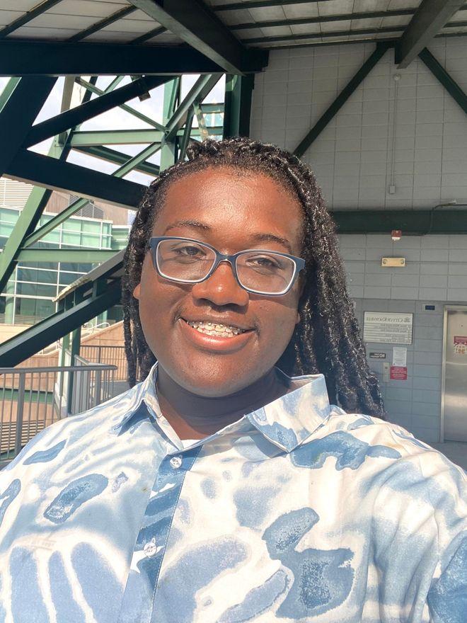 Aaron Hervey smiling in glasses and a blue patterned shirt
